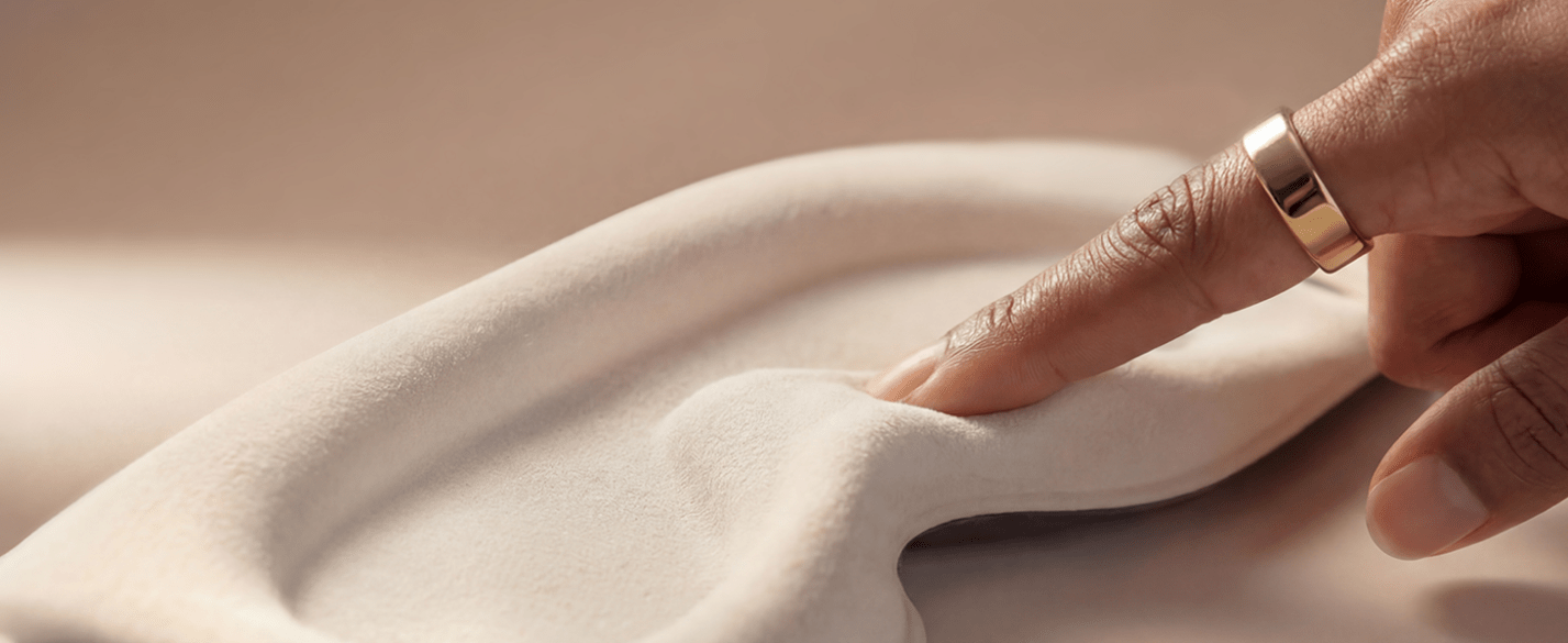 A finger touching the soft, skin-friendly inner lining material of the Sleenova sleep mask.